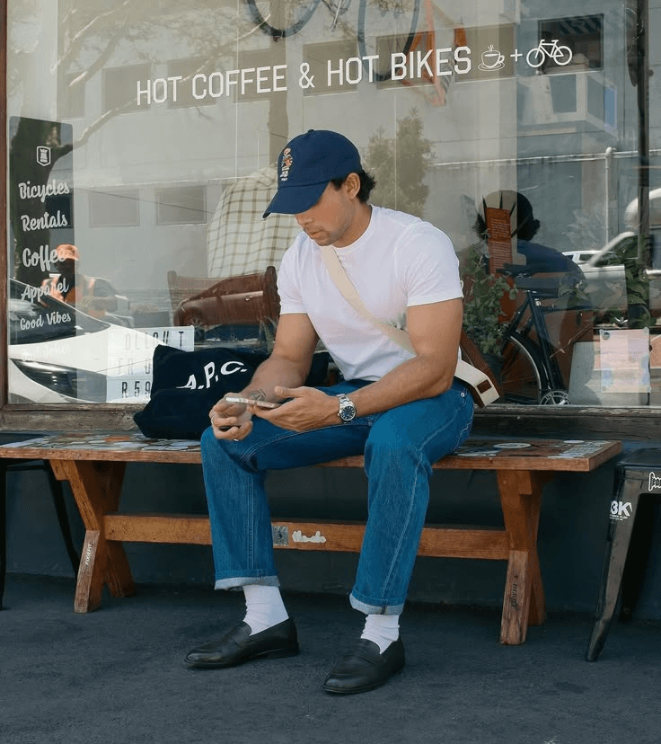 Person sitting outside a café, looking at their phone