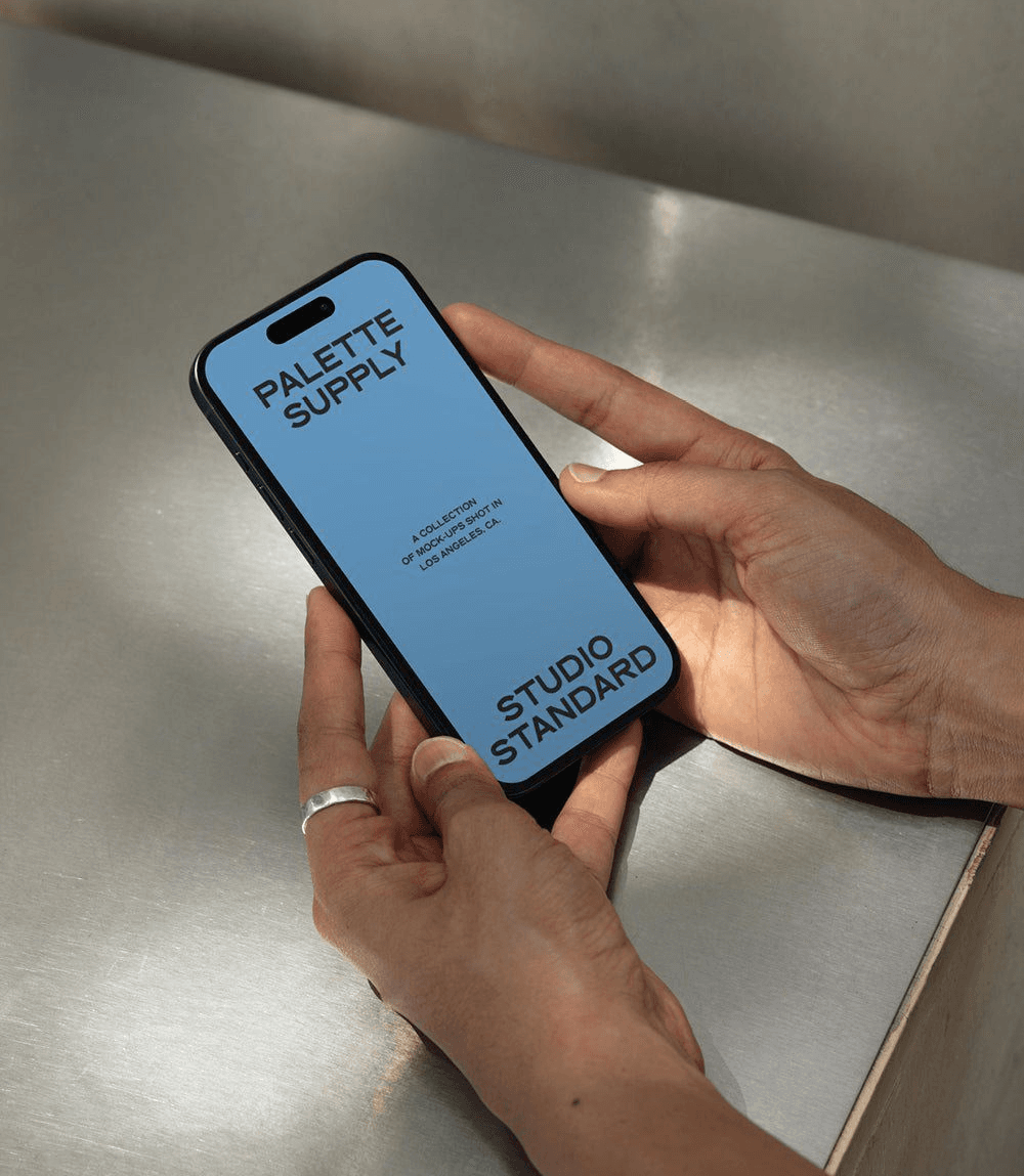Hands holding a smartphone on a brushed metal surface